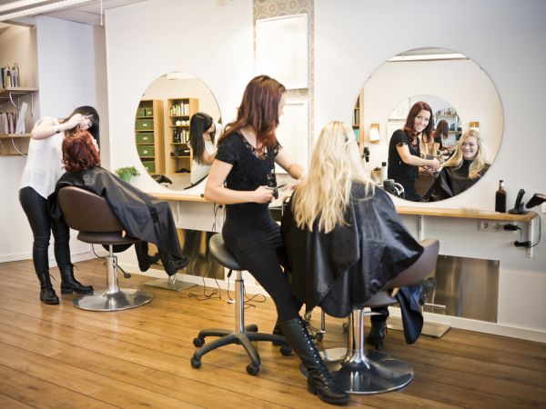Beauty salon image with clients in hair with smiling cosmetologists